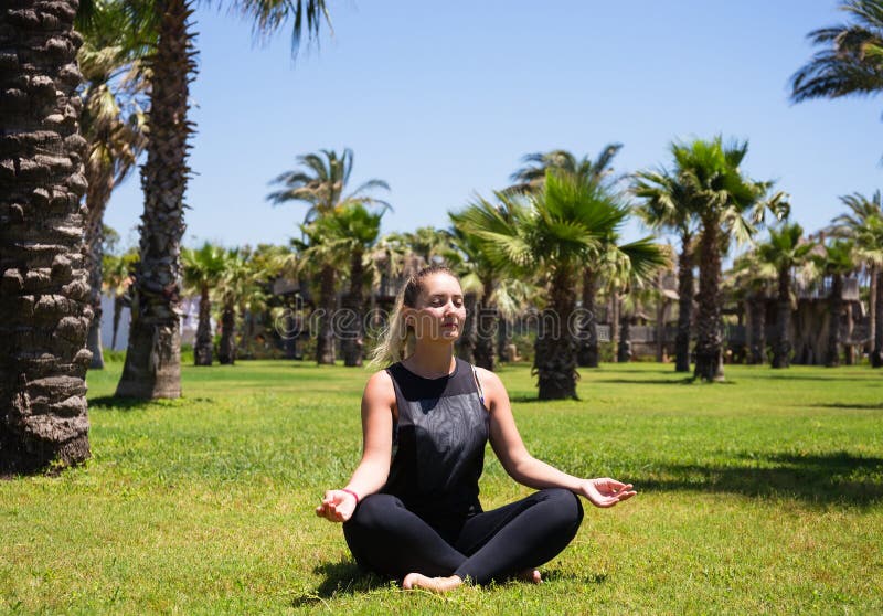 Meisje die yoga op het gras onder palmen doen royalty-vrije stock fotografie Meisje die yoga op het gras onder palmen doen royalty-vrije stock fotografie