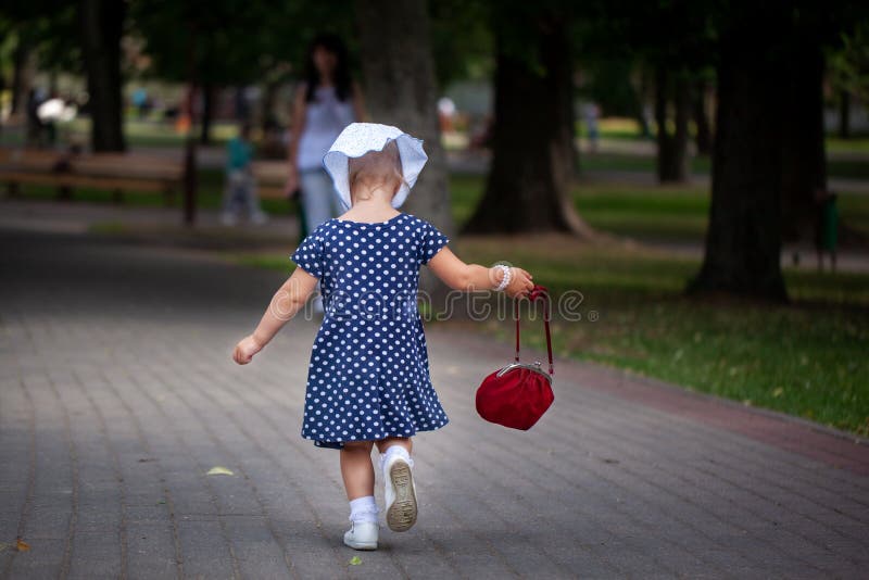 Meisje die in zakdoek en stipkleding het park in de zomer lopen Achter mening royalty-vrije stock foto Meisje die in zakdoek en stipkleding het park in de zomer lopen Achter mening royalty-vrije stock foto