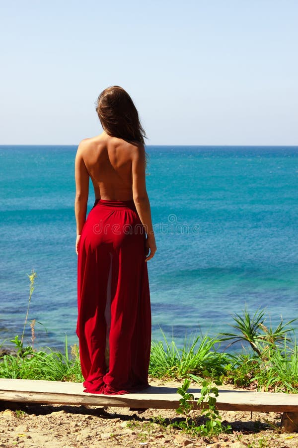 Meisje die zich topless in rode rok boven overzeese het kijken bevinden royalty-vrije stock afbeelding Meisje die zich topless in rode rok boven overzeese het kijken bevinden royalty-vrije stock afbeelding