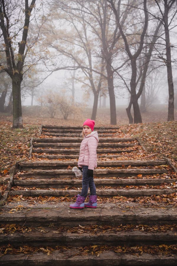 Meisje in een roze jasje die in een de herfst nevelig bos lopen in park stock foto's Meisje in een roze jasje die in een de herfst nevelig bos lopen in park stock foto's