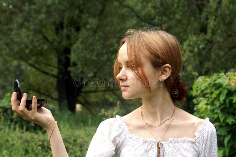 Young girl looking in pocket mirror. Young girl looking in pocket mirror