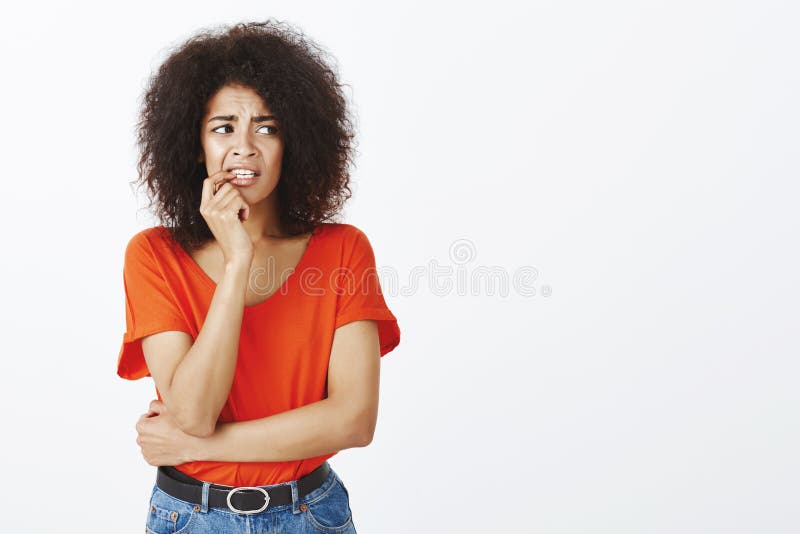 Meisje het bijten spijkers van nervositeit Portret die van bezorgd onzeker aantrekkelijk wijfje met afrokapsel, vinger houden stock fotografie Meisje het bijten spijkers van nervositeit Portret die van bezorgd onzeker aantrekkelijk wijfje met afrokapsel, vinger houden stock fotografie