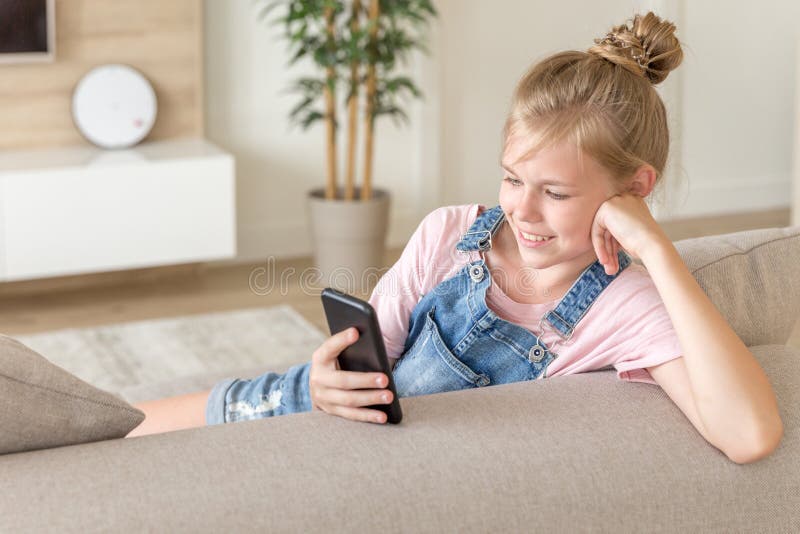 Meisje het spelen met een celtelefoon thuis op een laag stock afbeeldingen Meisje het spelen met een celtelefoon thuis op een laag stock afbeeldingen