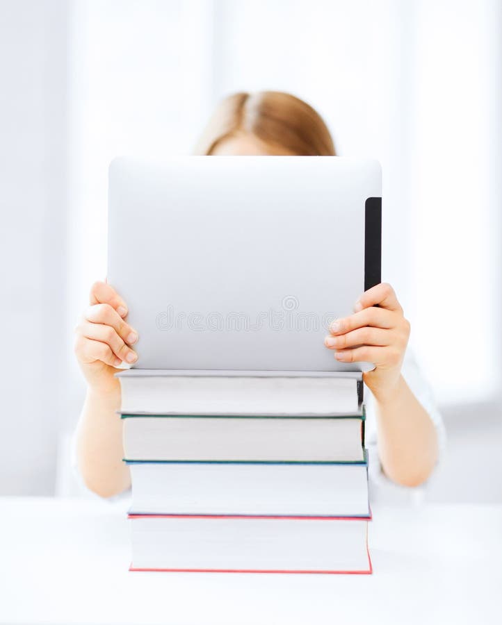 Meisje het verbergen achter tabletpc en boeken op school royalty-vrije stock foto's Meisje het verbergen achter tabletpc en boeken op school royalty-vrije stock foto's