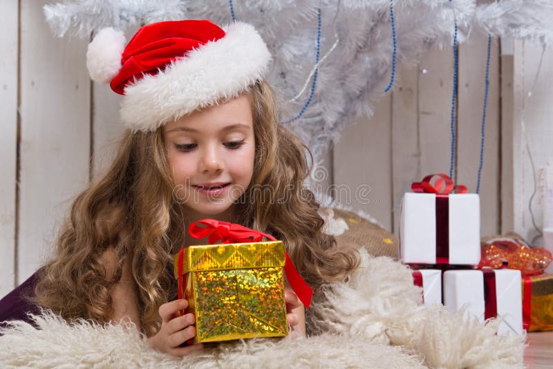 Little girl with christmas present in front of fir tree. Little girl with christmas present in front of fir tree