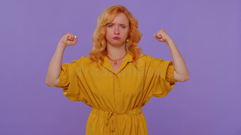 I am strong and independent. Long haired lovely girl showing biceps and looking confident, feeling power strength to fight for rights, energy to gain success win. Young woman on purple wall background. I am strong and independent. Long haired lovely girl showing biceps and looking confident, feeling power strength to fight for rights, energy to gain success win. Young woman on purple wall background