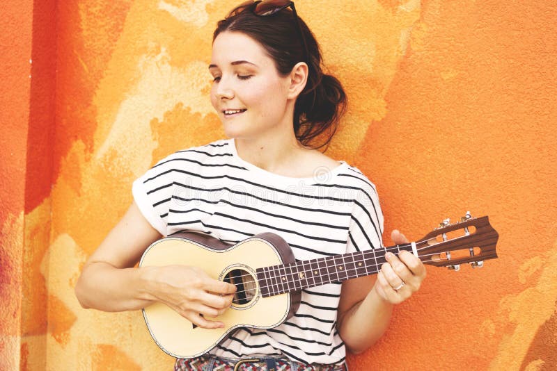 Meisje met gitaarukelele op de muurachtergrond stock afbeeldingen Meisje met gitaarukelele op de muurachtergrond stock afbeeldingen