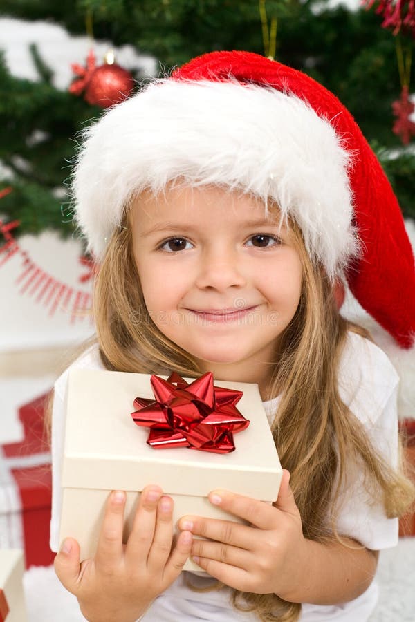 Adorable little girl holding present wearing a christmas hat - closeup. Adorable little girl holding present wearing a christmas hat - closeup