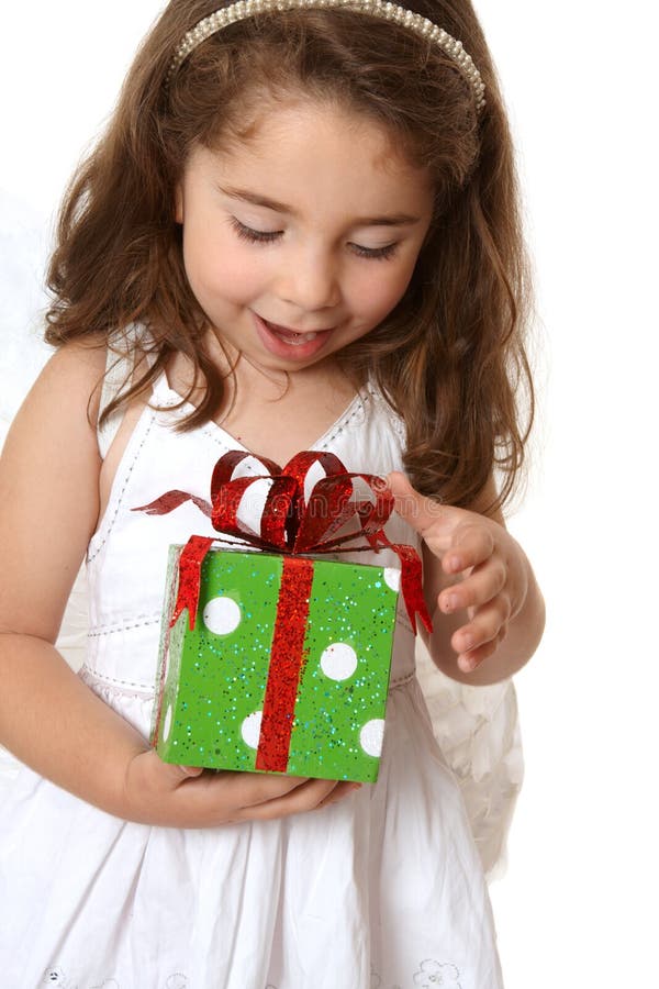 A little girl with browin hair looks down in delight at a Christmas present. A little girl with browin hair looks down in delight at a Christmas present