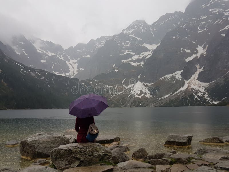 Meisje met parapluzitting op rotsen dichtbij meer stock foto Meisje met parapluzitting op rotsen dichtbij meer stock foto
