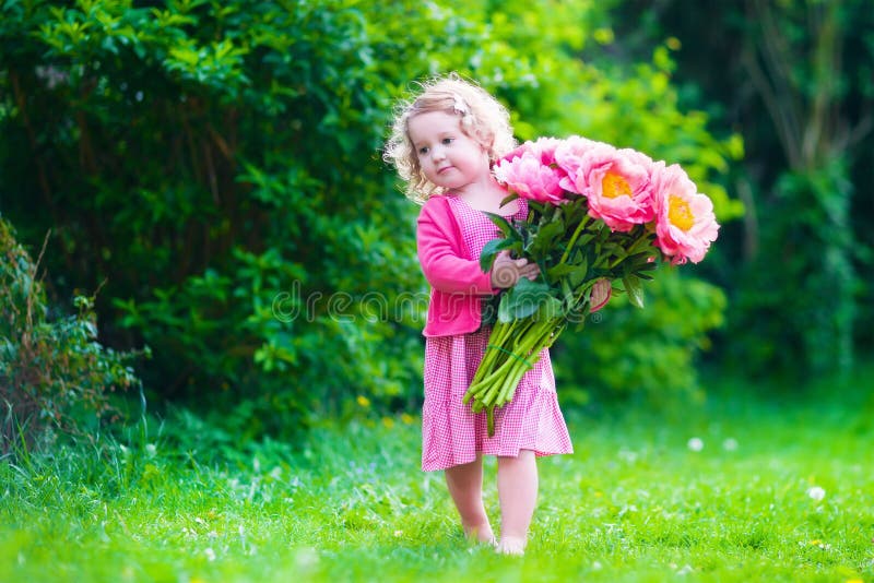Meisje met pioenbloemen in de tuin