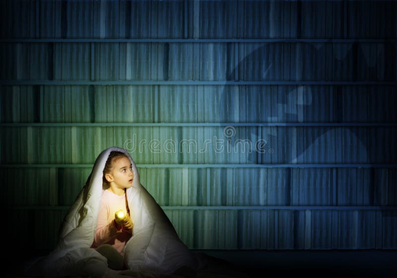 Image of a girl under the covers with a flashlight the night afraid of ghosts. Image of a girl under the covers with a flashlight the night afraid of ghosts