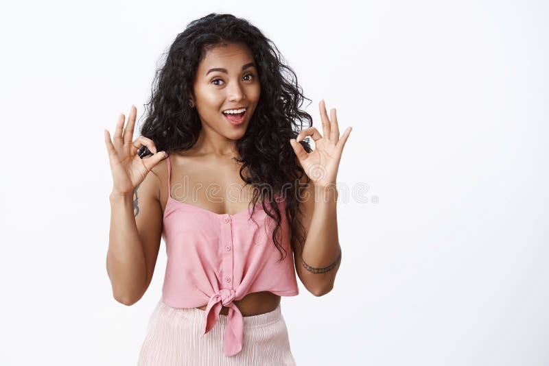 Girl impressed with good work. Attractive african-american female with curly hairstyle, showing okay, excellent gesture nod with approval, agree plan is great, smiling satisfied, white background. Girl impressed with good work. Attractive african-american female with curly hairstyle, showing okay, excellent gesture nod with approval, agree plan is great, smiling satisfied, white background.