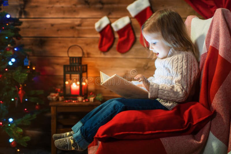 Meisje thuis met een Kerstmisboom, giften die een boekzitting lezen royalty-vrije stock foto's Meisje thuis met een Kerstmisboom, giften die een boekzitting lezen royalty-vrije stock foto's