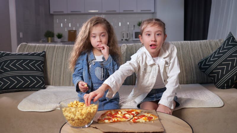 Meisjes broers en zussen eten popcorn en pizza en kijken thuis naar film