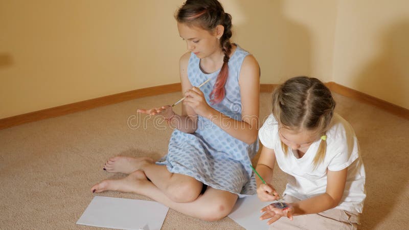 Meisjes die met waterverf op papier en op handen trekken