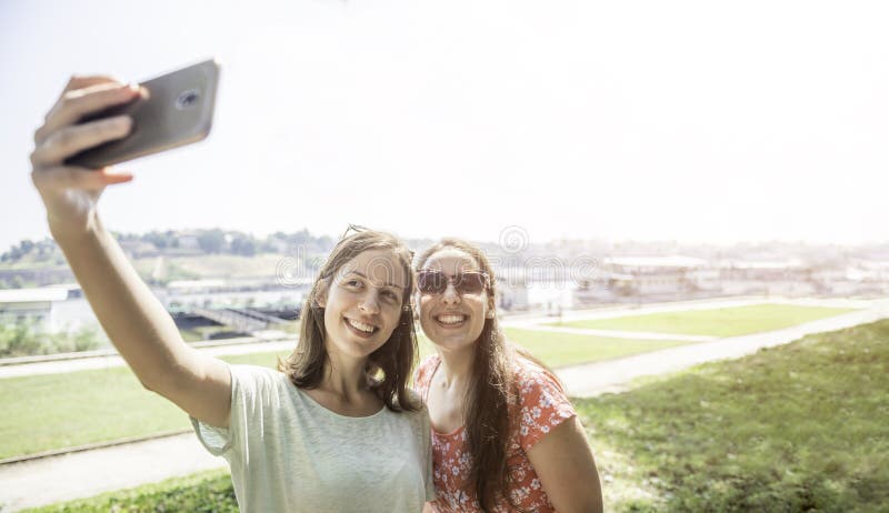 Meisjes die selfie samen hebbend pret in openlucht concept moderne gelukkige de levensstijl vrouwelijke beste vrienden van de vro stock afbeeldingen Meisjes die selfie samen hebbend pret in openlucht concept moderne gelukkige de levensstijl vrouwelijke beste vrienden van de vro stock afbeeldingen