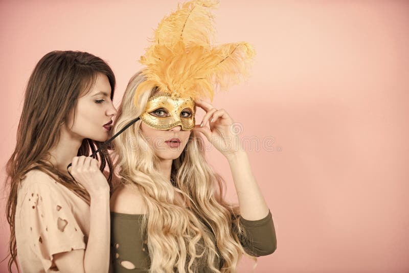 Girls with long hair on pink background. Woman put golden mask on girlfriend face. Carnival, party, holidays, celebration. Fashion, beauty, look concept. Love, lgbt, lesbian lifestyle copy space. Girls with long hair on pink background. Woman put golden mask on girlfriend face. Carnival, party, holidays, celebration. Fashion, beauty, look concept. Love, lgbt, lesbian lifestyle copy space