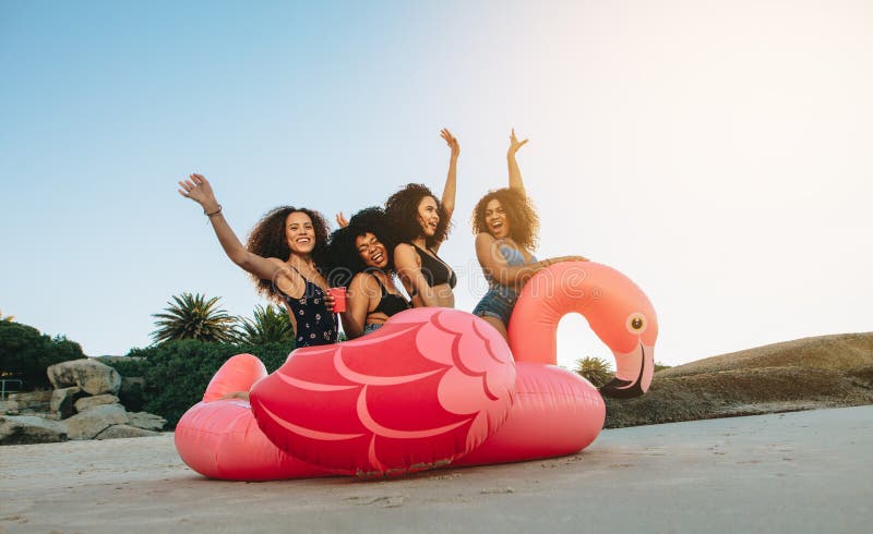 Meisjes op een opblaasbare zwaan bij het strand stock fotografie Meisjes op een opblaasbare zwaan bij het strand stock fotografie