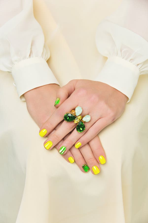 Closeup of woman hands with yellow and green nail polish. Closeup of woman hands with yellow and green nail polish