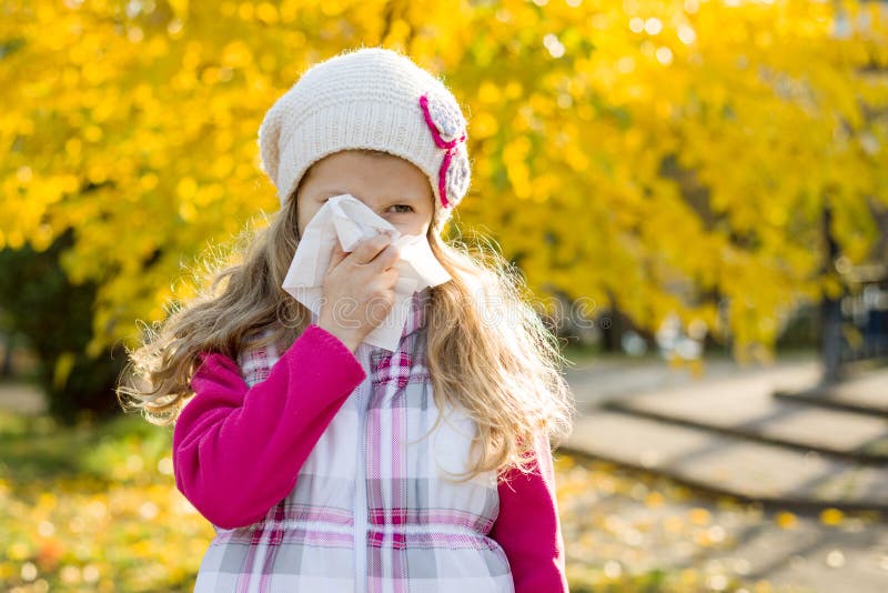 Meisjeskind met koud Rhinitis op de herfstachtergrond, griepseizoen, allergie lopende neus