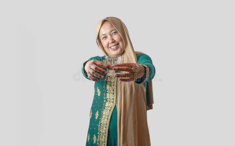 Mejande kvinnor i traditionell grön press som erbjuder ett glas framåt arkivbilder