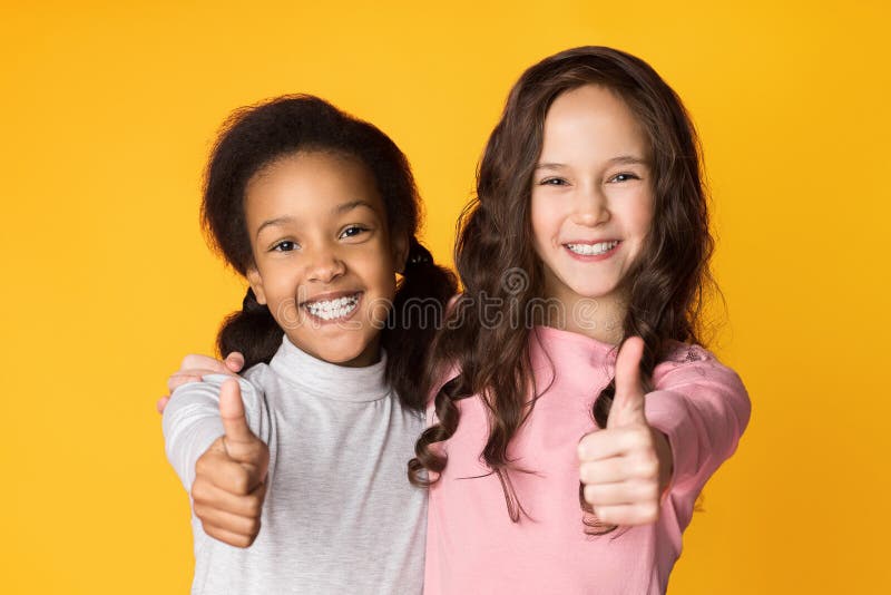 Mejores amigos que muestran los pulgares para arriba en fondo del estudio fotos de archivo Mejores amigos que muestran los pulgares para arriba en fondo del estudio fotos de archivo