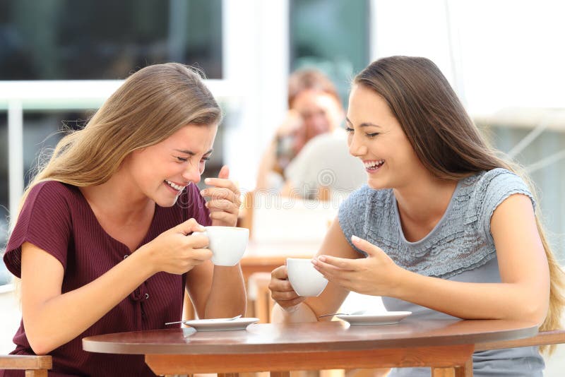 Two best friends laughing loud during a conversation sitting in a restaurant. Two best friends laughing loud during a conversation sitting in a restaurant