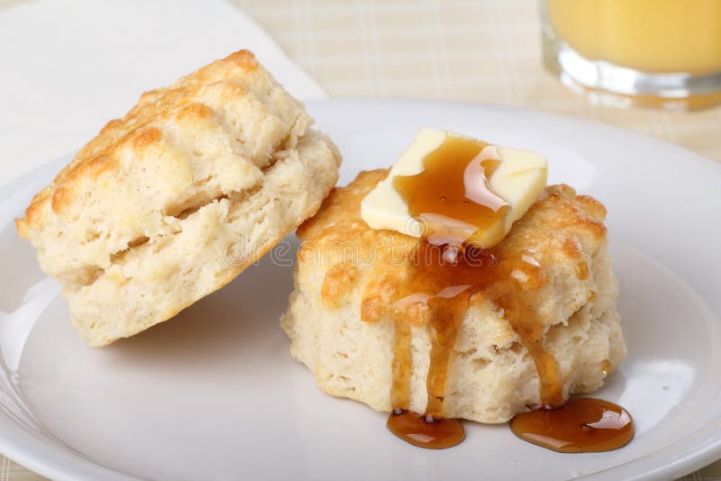 Two flaky biscuits with butter and honey on top. Two flaky biscuits with butter and honey on top