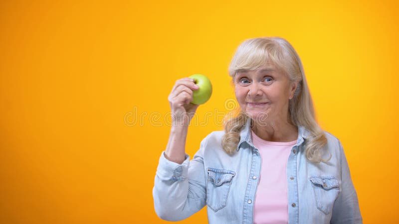 Mela verde fresca mordace di signora anziana ottimista, denti sani, stomatologia