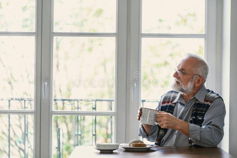 Melancholic grandfather eating breakfast all alone at the table