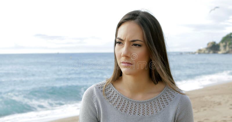 Melancholische vrouw die op het strand lopen