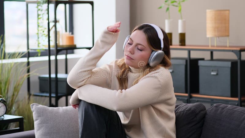 Melancholische vrouw luistert muziek thuis op sofa