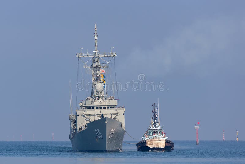 Melbourne, Australia - June 12, 2015: HMAS Melbourne FFG 05 Adelaide-class guided-missile frigate of the Royal Australian Navy docking at Station Pier in Melbourne with the assistance of tug boats