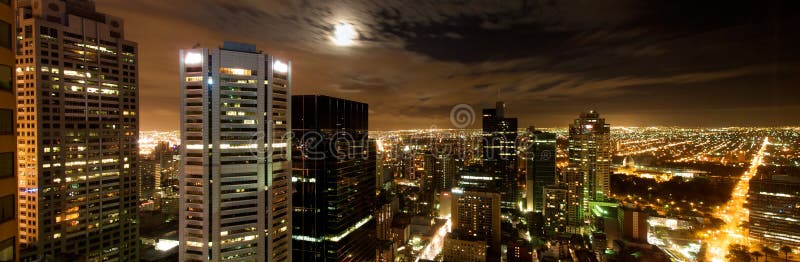 Melbourne night skyline buildings and light extending to the horizon with moody sky panorama. Melbourne night skyline buildings and light extending to the horizon with moody sky panorama