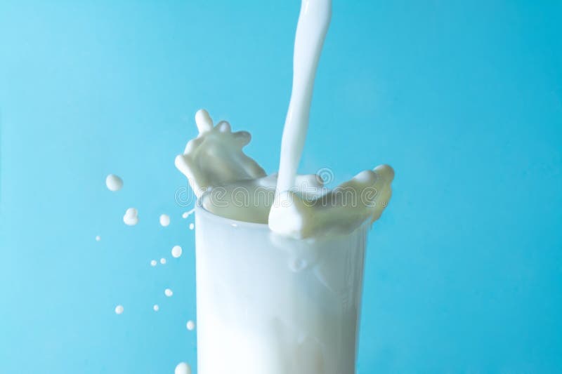 Melken Sie Spritzen im Glas und Jetstream von Milch in einem Glas auf einem blauen Hintergrund gießen lizenzfreie stockfotos Melken Sie Spritzen im Glas und Jetstream von Milch in einem Glas auf einem blauen Hintergrund gießen lizenzfreie stockfotos