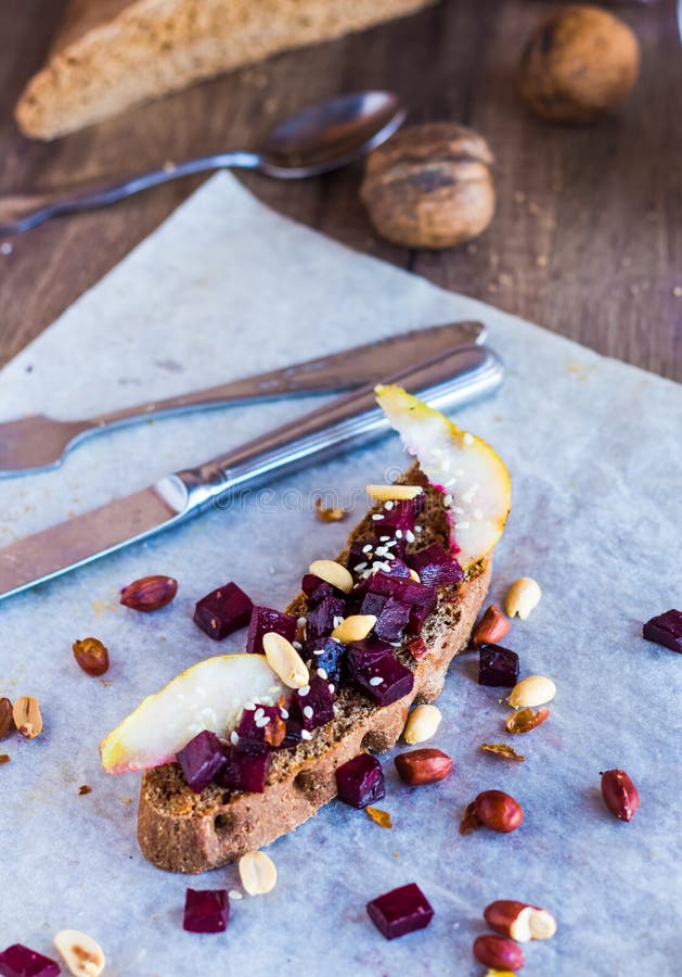 Mellanmålsmörgås med beta, valnötter och caramelized päron arkivbild Mellanmålsmörgås med beta, valnötter och caramelized päron arkivbild