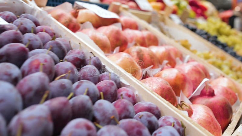 Melograni ed uva delle prugne delle pesche in scatole sul mercato