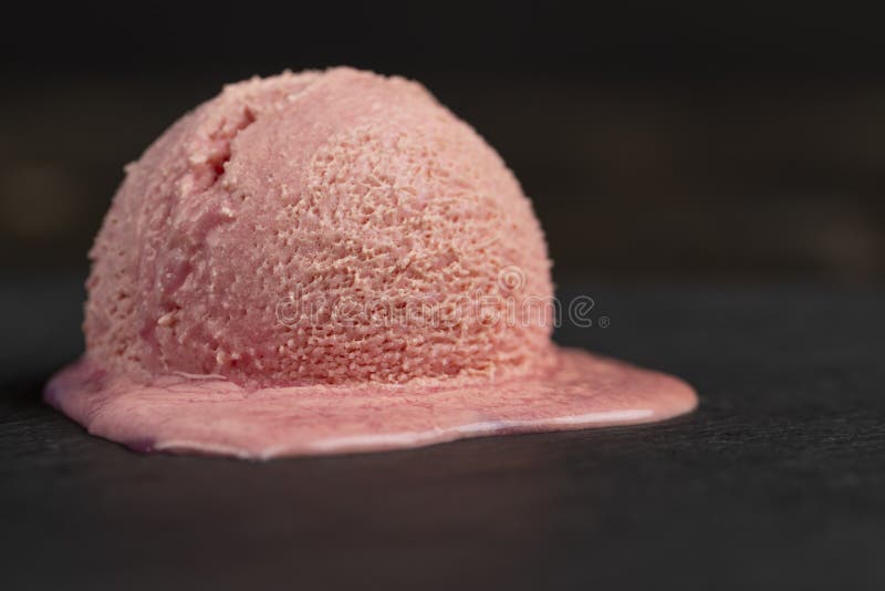 Melting ice cream on a dark slate , sweet cold pink ice stock images