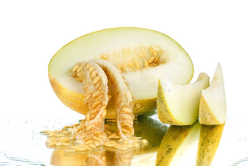Melón cortado amarillo con las semillas en el fondo blanco del espejo aislado cerca para arriba foto de archivo libre de regalías Melón cortado amarillo con las semillas en el fondo blanco del espejo aislado cerca para arriba foto de archivo libre de regalías
