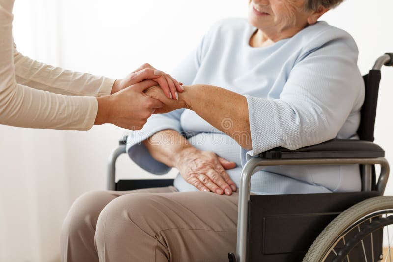 Close-up of family member helping disabled grandmother in a wheelchair. Close-up of family member helping disabled grandmother in a wheelchair