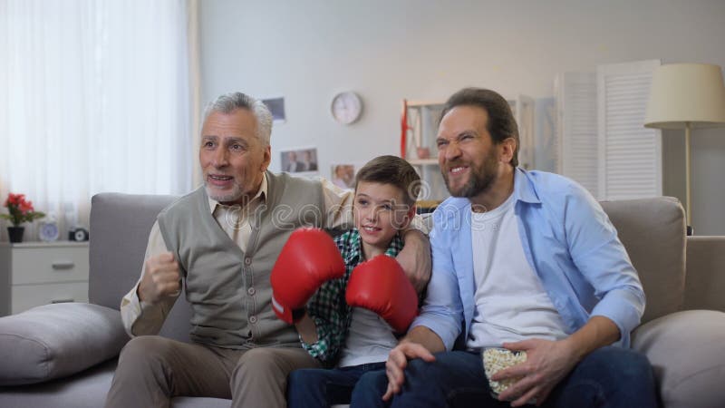 Membros da família entusiasmados do multiage que cheering para o jogo de observação do pugilista favorito na tevê