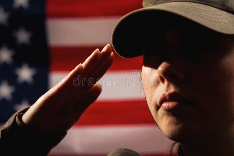 Memorial day. A female soldier in uniform salutes against the background of the American flag. Close-up portrait. The concept of