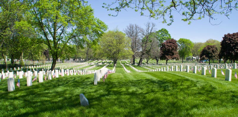 Memorial Day. A vast expanse of white grave markers at a Veteran's Cemetery, each adorned with US flags for Memorial Day royalty free stock image Memorial Day. A vast expanse of white grave markers at a Veteran's Cemetery, each adorned with US flags for Memorial Day royalty free stock image