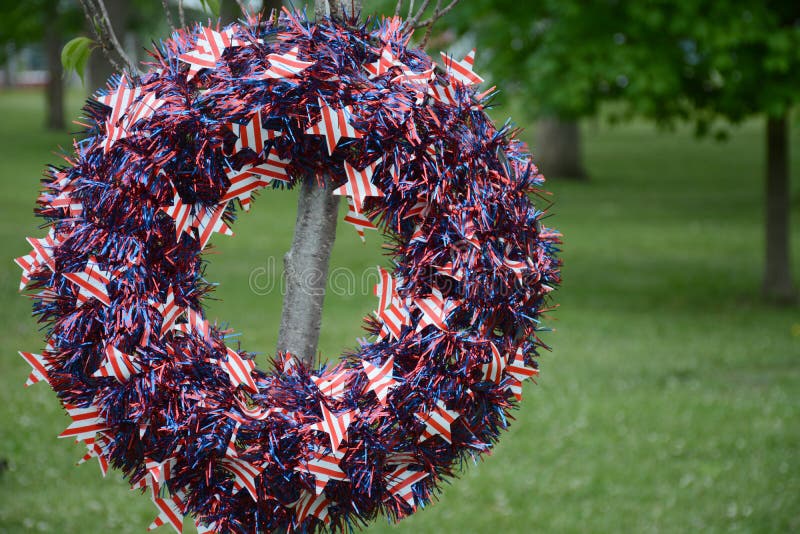 Memorial Day wreath. A Memorial Day wreath of red white and blue decorates a tree planted in the memory of a veteran royalty free stock photography Memorial Day wreath. A Memorial Day wreath of red white and blue decorates a tree planted in the memory of a veteran royalty free stock photography
