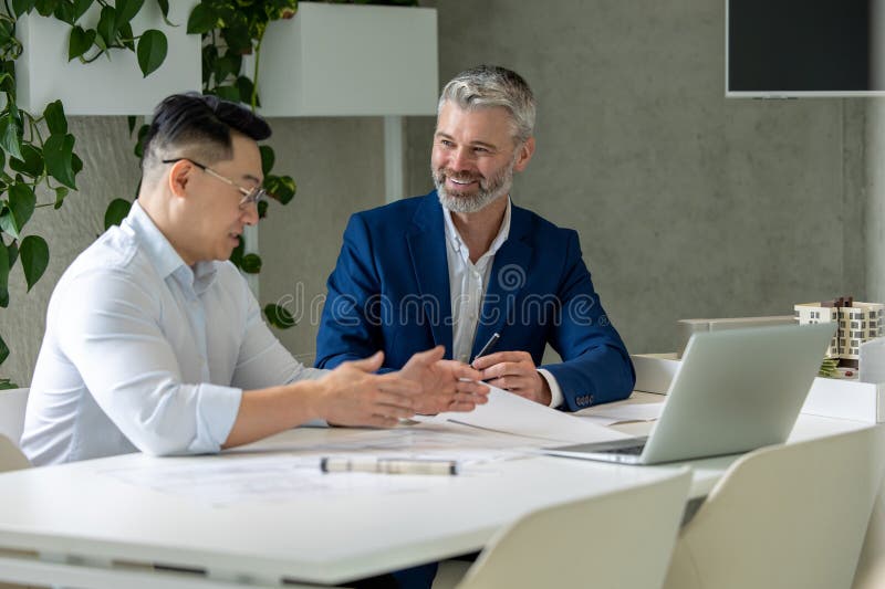 Men architects working on construction plans, engineers discussing on project in office. royalty free stock image