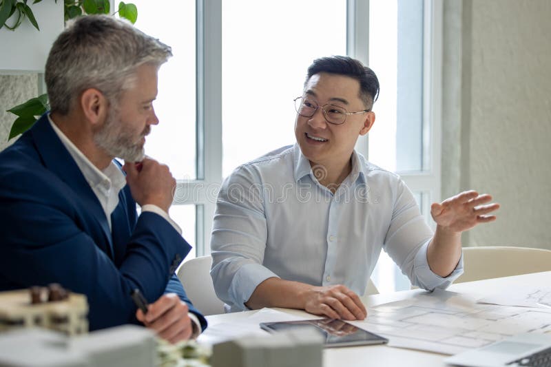 Men architects working on construction plans, engineers discussing on project in office. stock photo