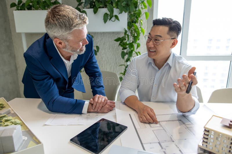 Men architects working on construction plans, engineers discussing on project in office. stock photography