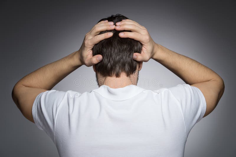 Men with headache. Rear view of men holding his head in hands while standing isolated on grey stock image