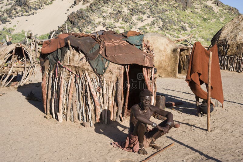 Man of the himba tribe in Namibia sitting in front of his hut